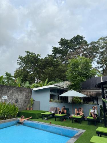 a group of people sitting in chairs by a swimming pool at The Jungle Hostel Canggu in Canggu