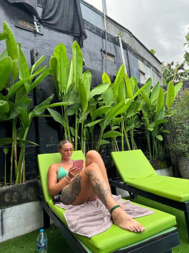 a woman sitting on a lawn chair with a book at The Jungle Hostel Canggu in Canggu