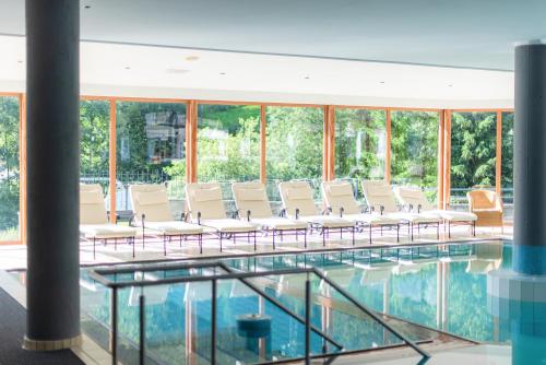 a room with chairs and a pool of water at Wellness-Sporthotel Ratschings in Racines