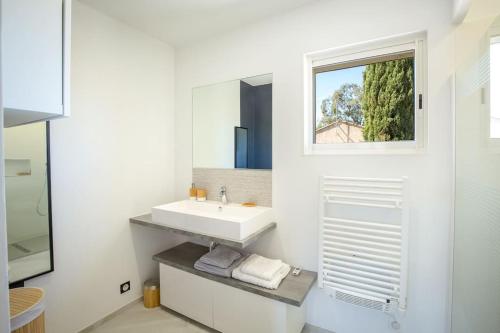 une salle de bain blanche avec un lavabo et une fenêtre dans l'établissement Caloussu-Calme-Moderne-Clim, à Roquebrune-sur Argens