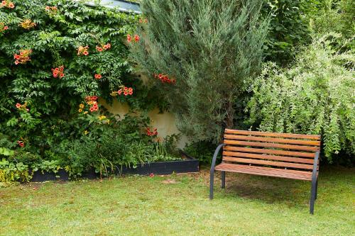 a wooden bench sitting in front of a garden at Guesthouse with 3 apartments, just outside Berlin, near to Tesla in Burig