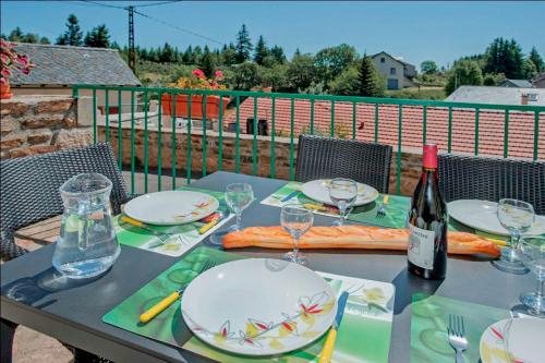 - une table avec des assiettes, des verres et une bouteille de vin dans l'établissement Gîte Gîtes de France 6/8 personnes, à Chasseradès