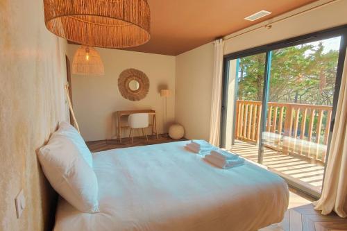 een slaapkamer met een groot bed en een groot raam bij Villa IrisJasmin jacuzzi vue mer in Lacanau
