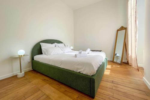- un lit vert dans une chambre avec un miroir dans l'établissement OIQIA • Berry, à Bourges