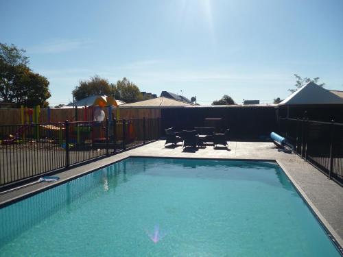 a swimming pool in a backyard with a playground at Cashel Court Motel in Christchurch