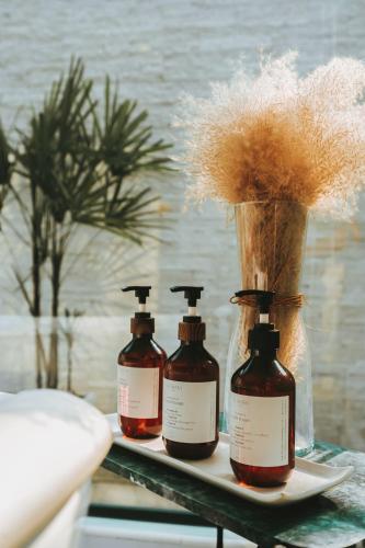 three bottles of hair products on a shelf with a vase at Te Mata Glamping in Nong Nam Daeng