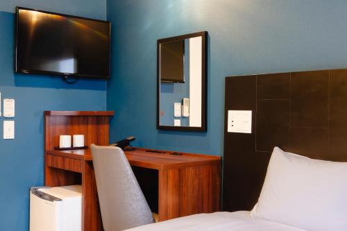 a bedroom with a desk with a bed and a mirror at KOKO HOTEL Shimbashi Onarimon - formerly Hotel Wing International Shimbashi Onarimon in Tokyo