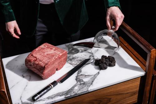 a person pouring food into a glass bowl on a table at QT Singapore in Singapore