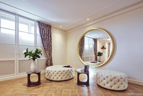 a living room with a round mirror and a ottoman at Parkhotel Gütersloh in Gütersloh