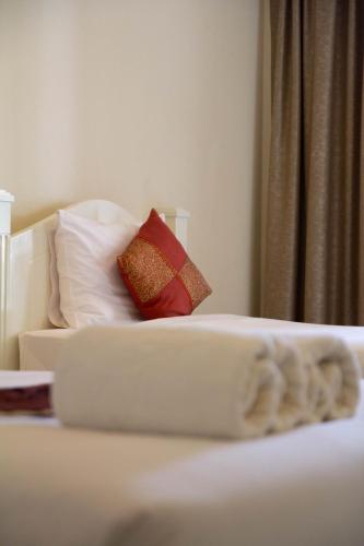 a white bed with two red pillows on it at Grandsmile Wellness Resort in Pattaya