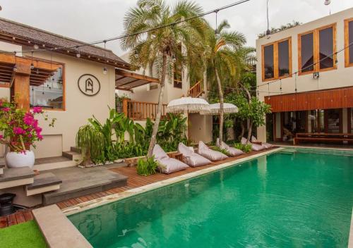 a villa with a swimming pool and a house at Nyaman Hostel in Canggu