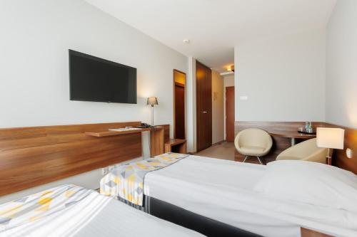 a hotel room with two beds and a flat screen tv at Hotel Tarnovia in Tarnów