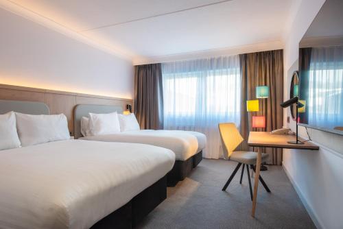 a hotel room with two beds and a television at Holiday Inn Edinburgh Zoo by IHG in Edinburgh