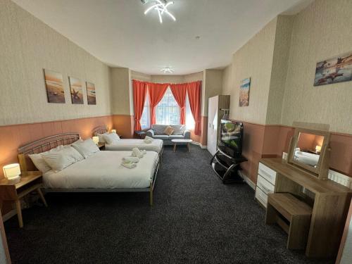 a bedroom with a bed and a tv and a couch at The Paradise Guest House in Great Yarmouth