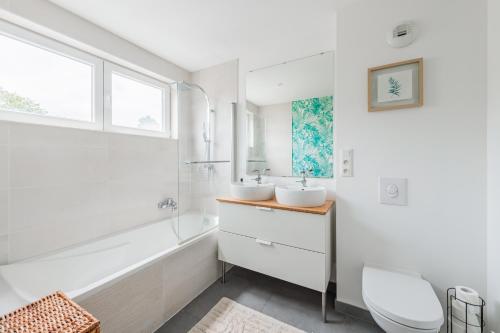 La salle de bains blanche est pourvue de 2 lavabos et d'une baignoire. dans l'établissement Le clos des Aviateurs - Belle maison à Strasbourg, à Strasbourg