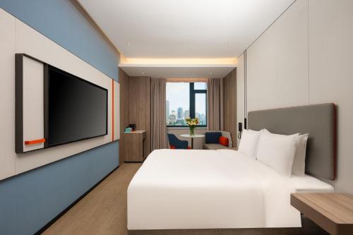 a bedroom with a white bed and a flat screen tv at Holiday Inn Express Shanghai Jing'an Temple by IHG in Shanghai