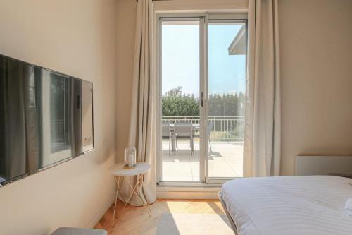- une chambre avec un lit et une grande porte coulissante en verre dans l'établissement Joli T3 avec terrasse et parking, Écully, à Écully