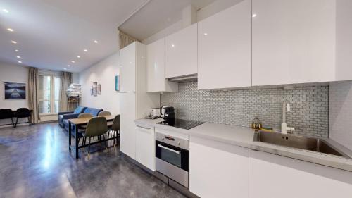 une cuisine avec des placards blancs et une salle à manger dans l'établissement Bluestay 63 - Appartement cozy, Paris centre, à Paris