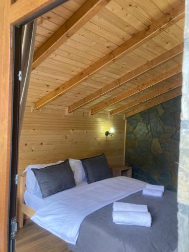 a bed in a room with a wooden ceiling at Bujtina Arturi in Valbonë