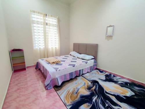 a bedroom with a bed and a rug on the floor at CASA ADELIA GUESTHOUSE 3b in Cukai