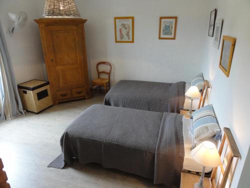 a bedroom with two beds and a table and a chair at Gîte La Jaujon in Lablachère