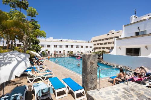 a group of people sitting around a swimming pool at Dialez Holidays - Rebecca in Playa de las Americas