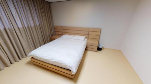 a small bedroom with a bed with white sheets at High1 Condominium in Jeongseon
