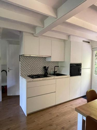 a white kitchen with white cabinets and a table at La petite maison Durbuy in Durbuy