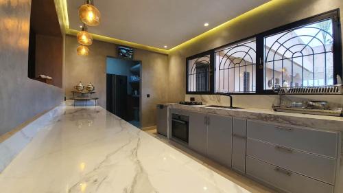 a large kitchen with white marble counter tops and windows at Ferme ADAM Agafay Marrakech in Marrakech