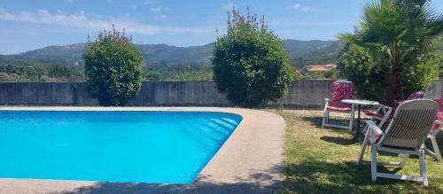 a swimming pool with chairs and a table next to a fence at Lugar de Levides in Levide