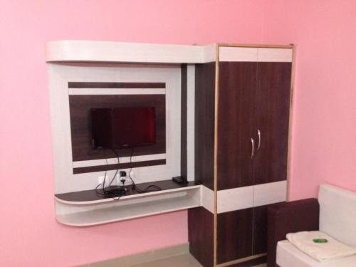 a tv sitting in a cabinet in a pink room at Hotel Viraat Inn in Gaya