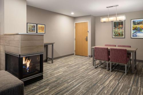 a waiting room with a fireplace and a table and chairs at Hampton Inn Spokane Airport in Spokane