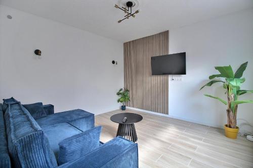 un salon avec un canapé bleu et une télévision dans l'établissement Le Cocon Caché, à Valenciennes