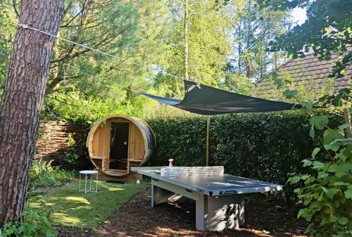 a ping pong table and a hammock in a garden at Wellnesshuis met jacuzzi en sauna in het bos in Lunteren