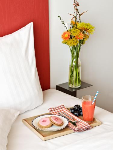 a tray with a plate of food and a drink on a bed at Dahei Apartment Hotel in Copenhagen