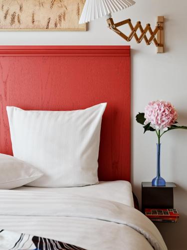 a bed with a red headboard and a vase of flowers at Dahei Apartment Hotel in Copenhagen