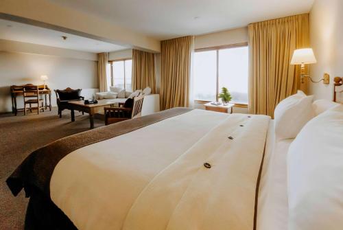 a hotel room with a large bed and a living room at Wyndham Garden Ushuaia Hotel del Glaciar in Ushuaia