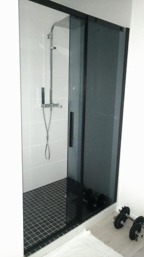 une douche avec une porte vitrée dans une salle de bain dans l'établissement Superbe chambre dans maison neuve, propre et bien aérée, à La Verrière