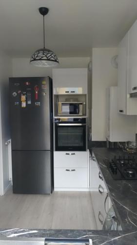 La cuisine est équipée d'un réfrigérateur noir et d'un four micro-ondes. dans l'établissement Superbe chambre dans maison neuve, propre et bien aérée, à La Verrière