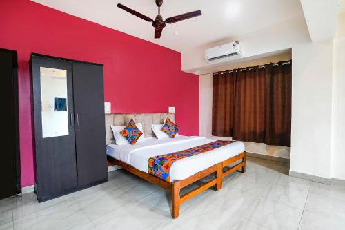 a bedroom with a large bed with a red wall at FabExpress Sunset Residency - Nr Apollo Hospitals in Mumbai