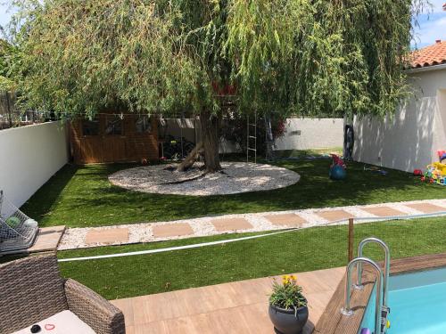 une cour avec un arbre et une piscine dans l'établissement La maison de Julie et Franck, à Montescot