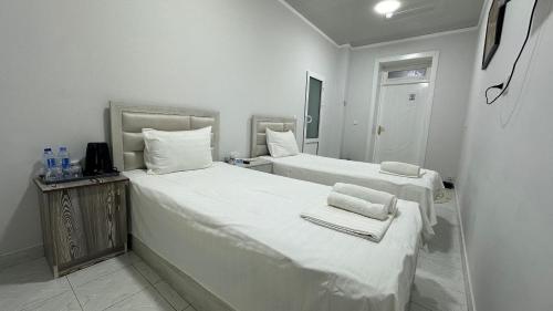 two beds in a white room with towels on them at Sultan hotel boutique in Andizhan