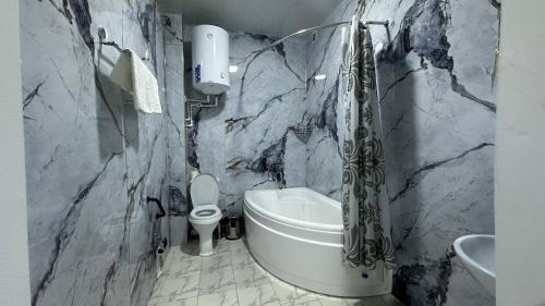 a bathroom with a tub and a toilet and a sink at Sultan hotel boutique in Andizhan