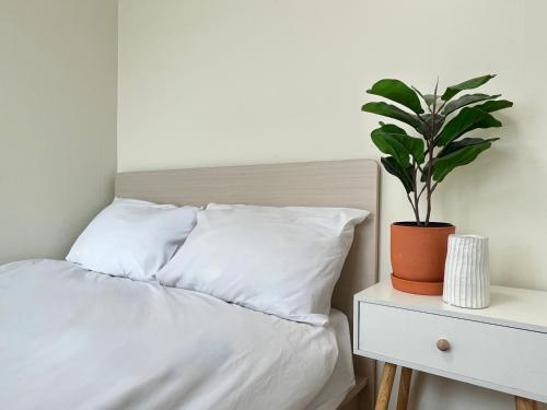 a bed with white sheets and a plant on a nightstand at Jnineguesthouse in Seoul