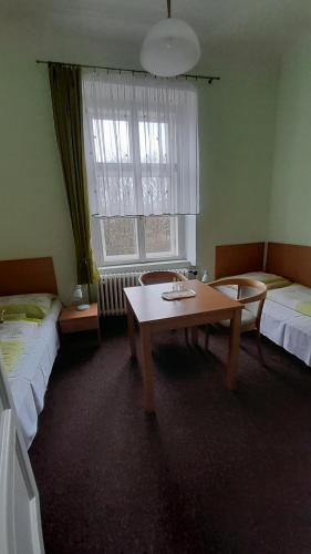 a room with two beds and a table and a window at Penzion na zámku Bartošovice in Nový Jičín