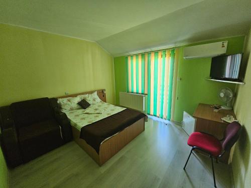 a green room with a bed and a chair in it at Pensiunea Esential in Ocnele Mari