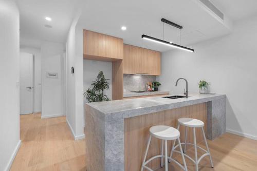 a kitchen with a counter and two stools at 4 Bedrooms Home Ormond private Parkings in Carnegie
