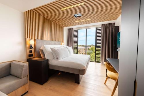 a bedroom with a bed and a chair and a window at YOTELPAD London Stratford in London