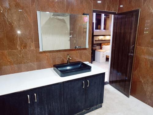 Un baño con un lavabo negro y un espejo. en Heminn Stay Ramapuram, en Chennai