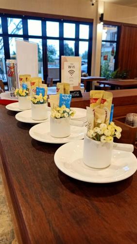 ein langer Tisch mit weißen Tellern, auf denen Blumen lagen in der Unterkunft Zenery Lake Resort in Ban Don Klang